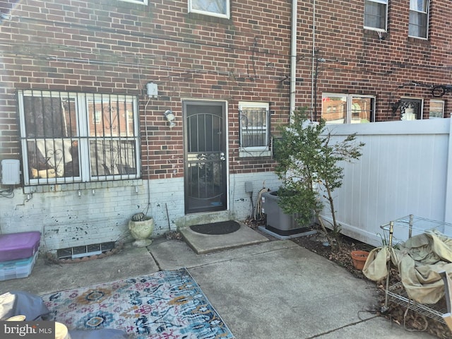 property entrance featuring brick siding and cooling unit