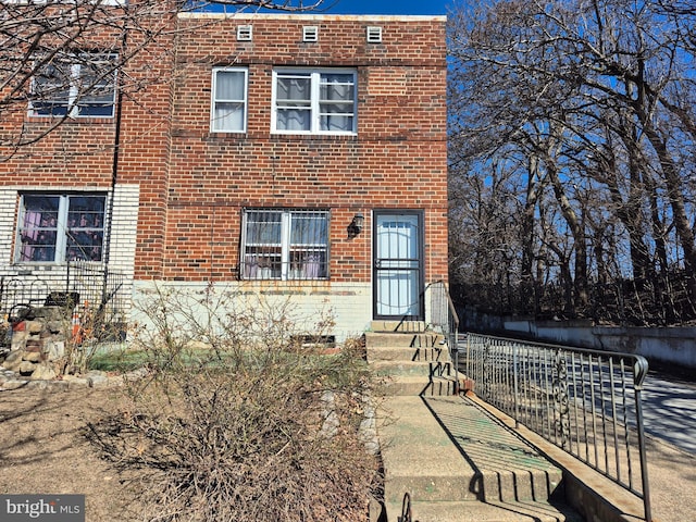 view of front facade with entry steps, fence, and brick siding