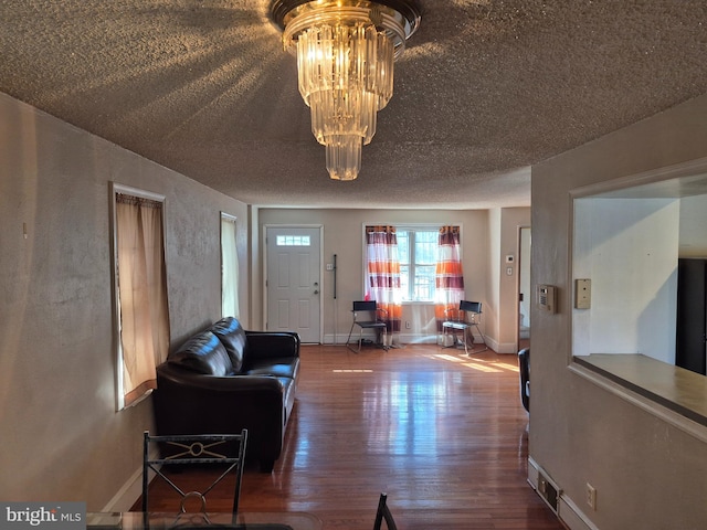 foyer with an inviting chandelier, a textured ceiling, baseboards, and wood finished floors