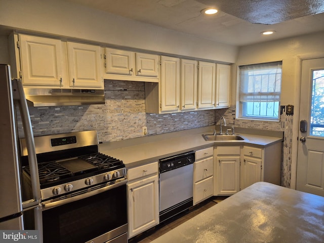 kitchen with under cabinet range hood, a sink, white cabinetry, light countertops, and appliances with stainless steel finishes