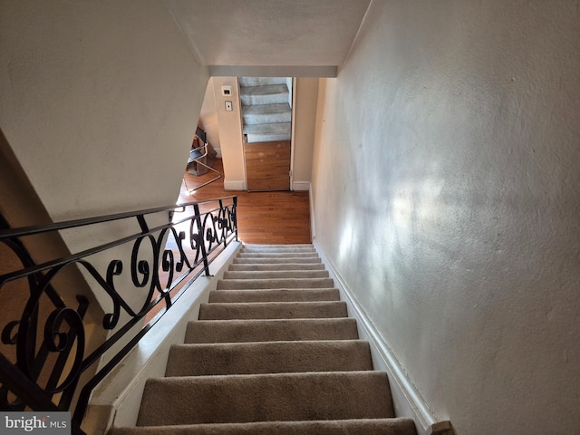 staircase with a textured wall and baseboards