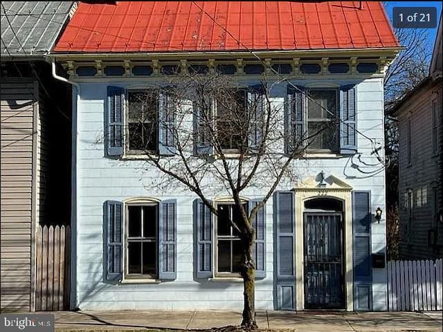 doorway to property featuring a standing seam roof, metal roof, and fence