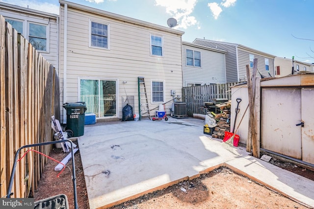 back of house with central AC unit, a fenced backyard, an outdoor structure, a storage unit, and a patio area