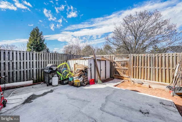 view of patio / terrace with a gate, a fenced backyard, a shed, a grill, and an outdoor structure