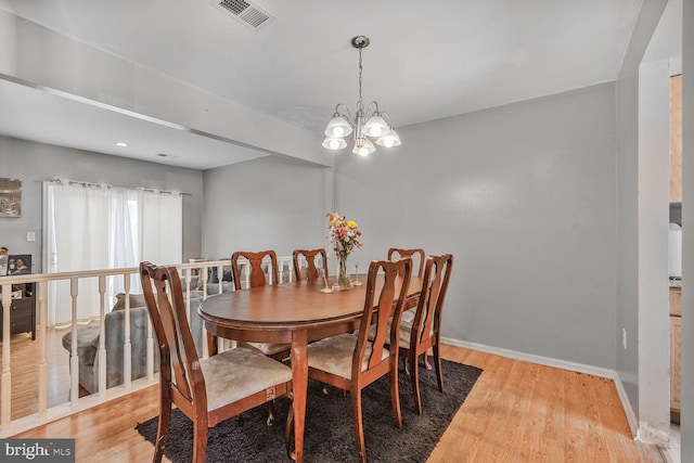 dining space with visible vents, an inviting chandelier, baseboards, and light wood-style floors