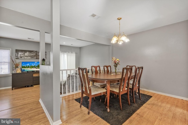 dining room featuring a notable chandelier, wood finished floors, visible vents, and baseboards