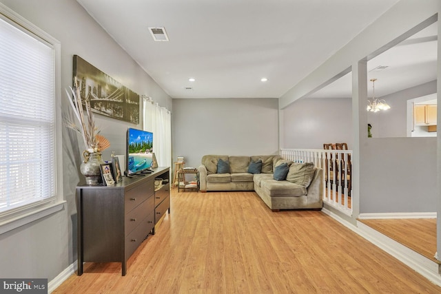 living room featuring baseboards, visible vents, a chandelier, and light wood-type flooring