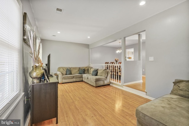 living area featuring visible vents, a notable chandelier, recessed lighting, light wood finished floors, and baseboards