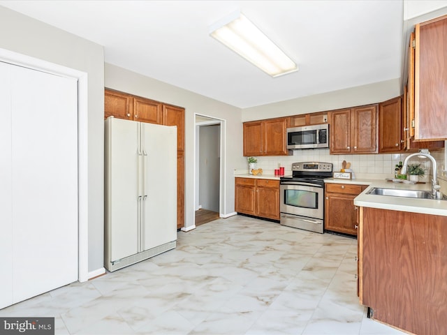 kitchen with appliances with stainless steel finishes, sink, and decorative backsplash