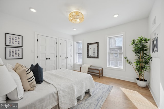 bedroom with multiple closets and light wood-type flooring