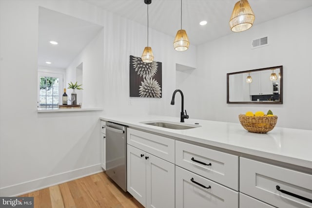 kitchen with sink, white cabinetry, decorative light fixtures, light wood-type flooring, and dishwasher