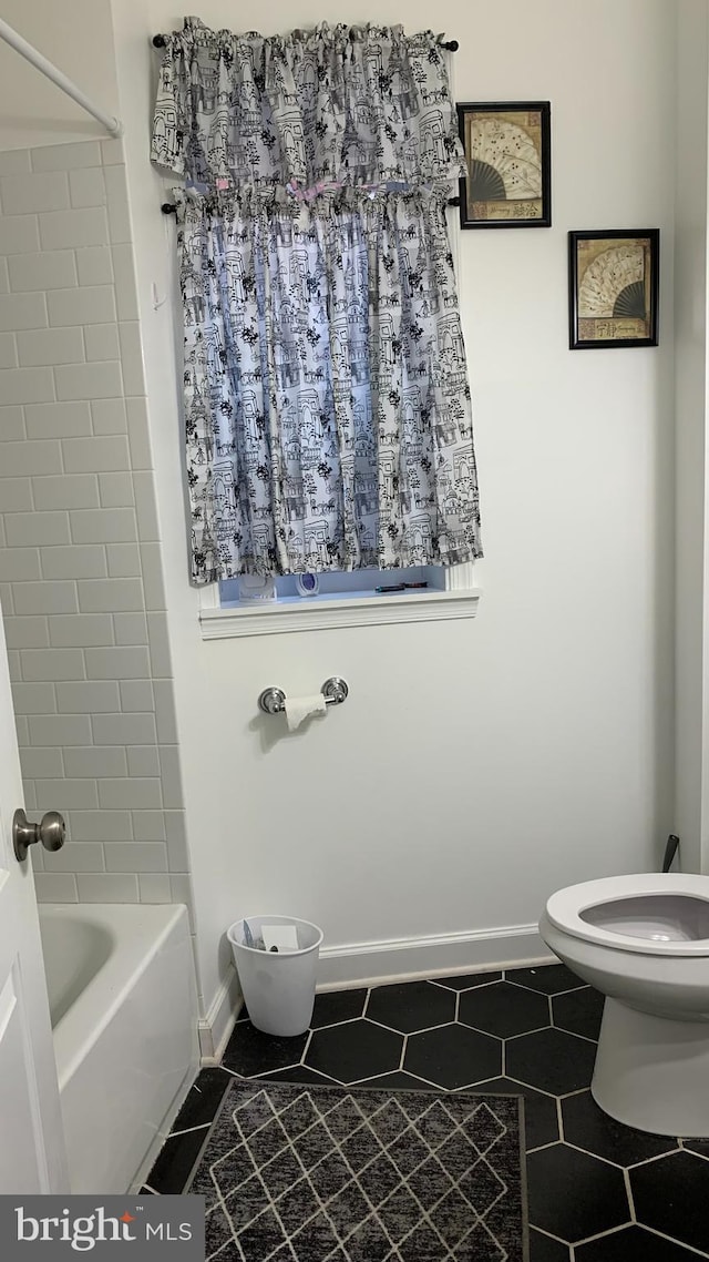 bathroom featuring tiled shower / bath, tile patterned floors, and toilet