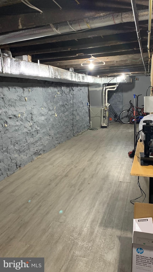 basement with wood-type flooring and heating unit