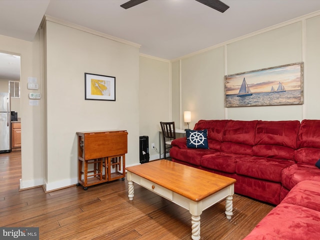 living room featuring hardwood / wood-style floors, ornamental molding, and ceiling fan