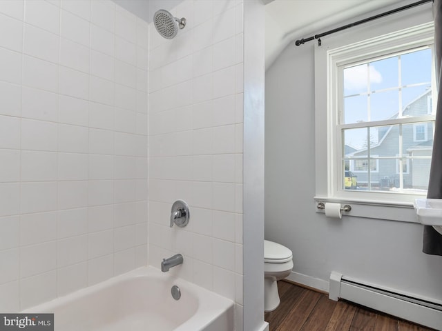 bathroom featuring hardwood / wood-style flooring, tiled shower / bath, baseboard heating, and toilet