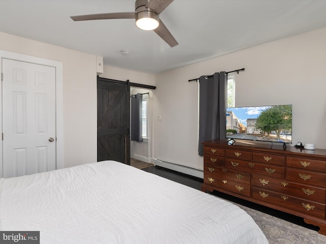 bedroom with a barn door, a baseboard heating unit, and ceiling fan