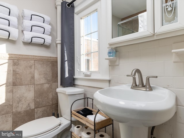 bathroom with tile walls, sink, and toilet