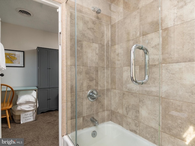 bathroom featuring a textured ceiling and shower / bath combination with glass door