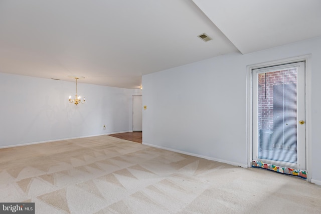 carpeted empty room with an inviting chandelier