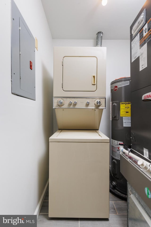 clothes washing area featuring electric panel, electric water heater, and stacked washer / dryer