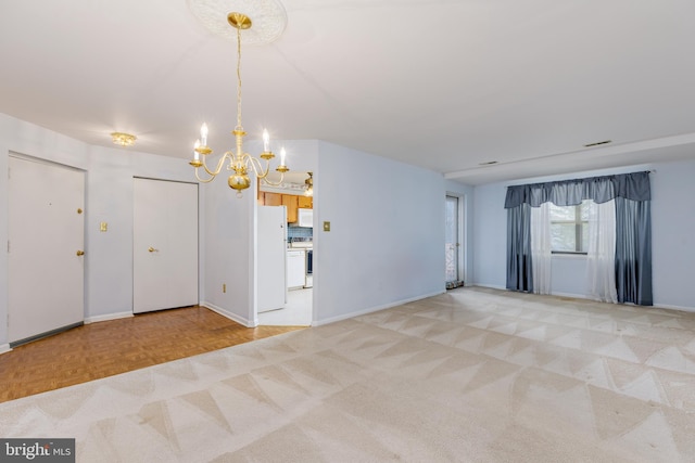 spare room featuring parquet flooring and an inviting chandelier