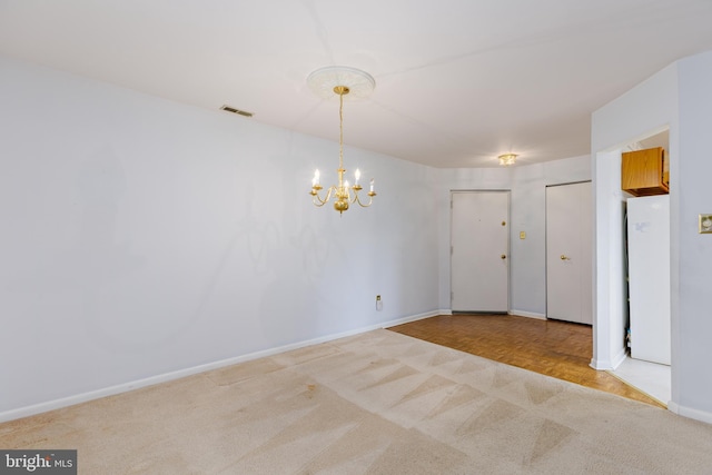 spare room with an inviting chandelier and light parquet floors