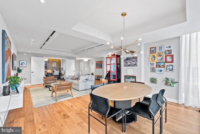 dining area featuring light hardwood / wood-style flooring and a tray ceiling