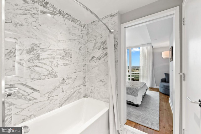 bathroom featuring tiled shower / bath combo and hardwood / wood-style flooring