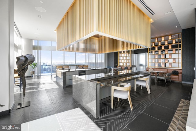 kitchen with a wall of windows, kitchen peninsula, sink, and dark tile patterned floors