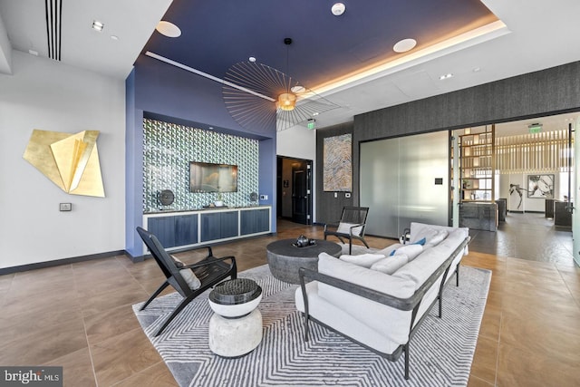 living room featuring tile patterned flooring, a tray ceiling, and a towering ceiling