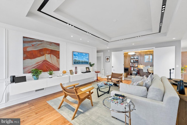 living room featuring a raised ceiling and light wood-type flooring