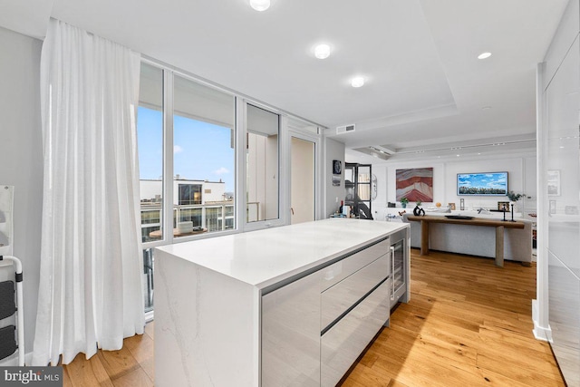 kitchen with wine cooler, a center island, and light hardwood / wood-style floors