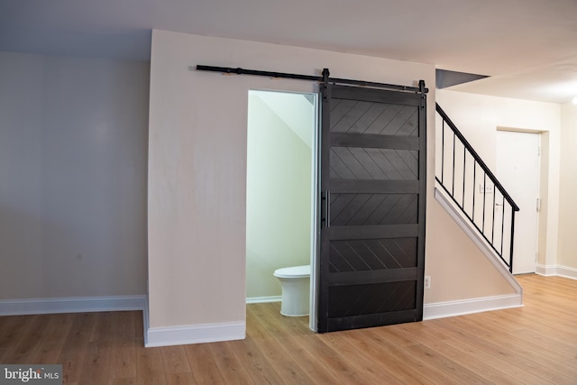 stairway featuring wood finished floors, baseboards, and a barn door