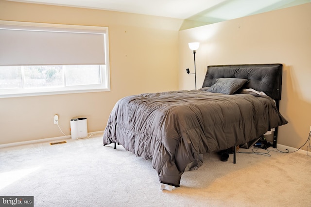 bedroom featuring baseboards, visible vents, and light colored carpet