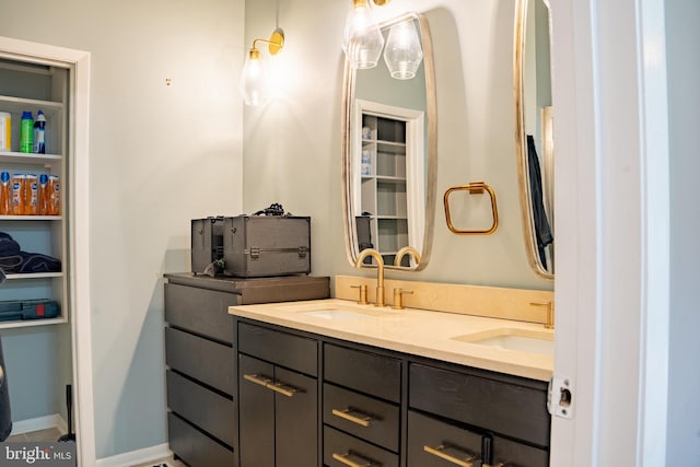 bathroom with a closet, a sink, baseboards, and double vanity