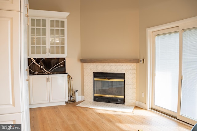 unfurnished living room featuring light wood-style flooring, baseboards, and a tile fireplace