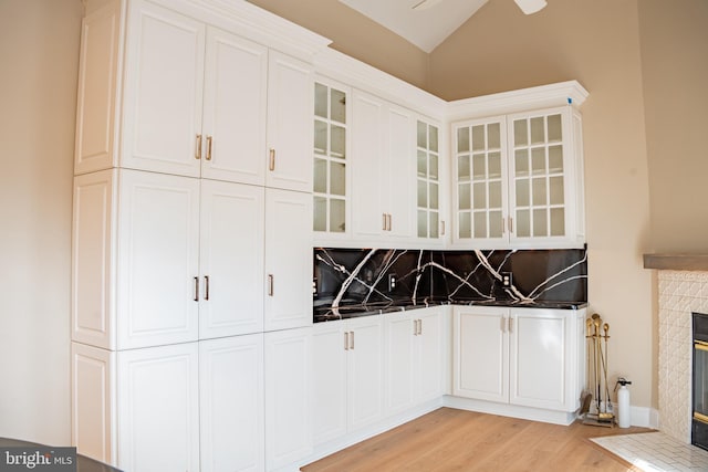 kitchen with dark countertops, a fireplace, glass insert cabinets, and white cabinets