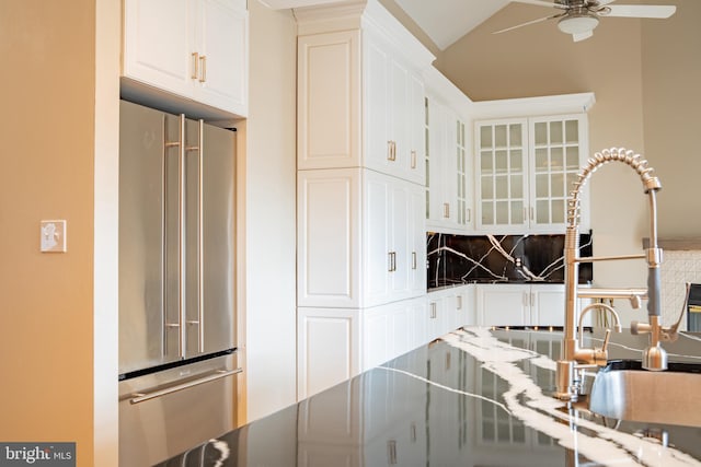 kitchen with backsplash, glass insert cabinets, a ceiling fan, white cabinets, and high end refrigerator