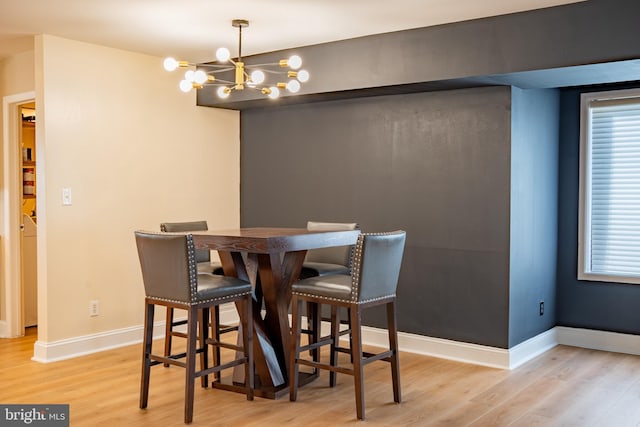 dining space featuring light wood-style flooring, baseboards, and a notable chandelier