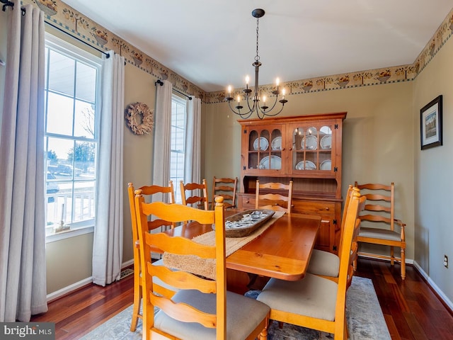 dining area with dark hardwood / wood-style flooring and an inviting chandelier