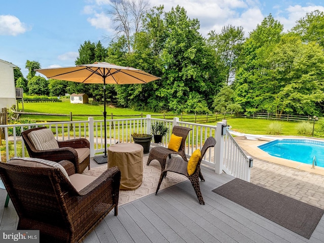 wooden deck featuring a yard, a fenced in pool, and a shed