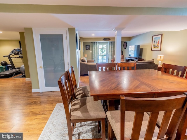 dining room featuring ornate columns and light wood-type flooring