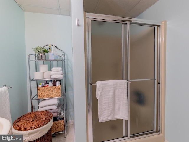 bathroom with a paneled ceiling, a shower with shower door, and tile patterned flooring