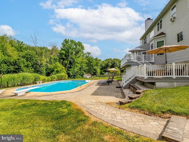 view of swimming pool featuring a wooden deck, a patio, a diving board, and a lawn