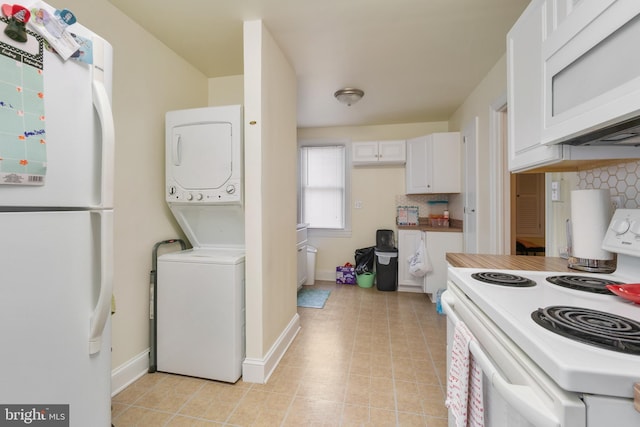 kitchen with tasteful backsplash, baseboards, stacked washer and clothes dryer, white appliances, and white cabinetry