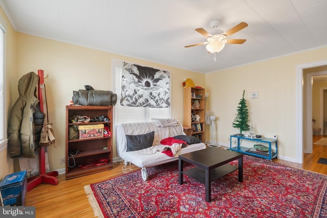 living area with ceiling fan, ornamental molding, and wood finished floors
