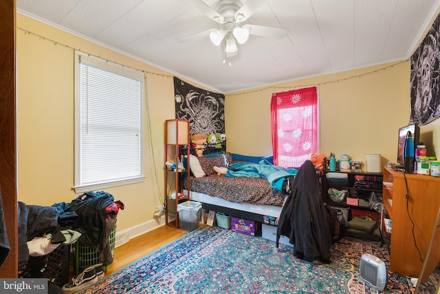 bedroom with ceiling fan, ornamental molding, and wood finished floors