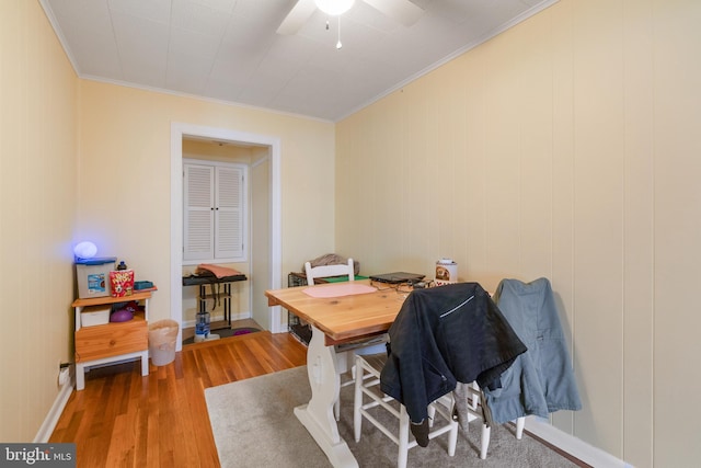 dining space with baseboards, ornamental molding, a ceiling fan, and wood finished floors