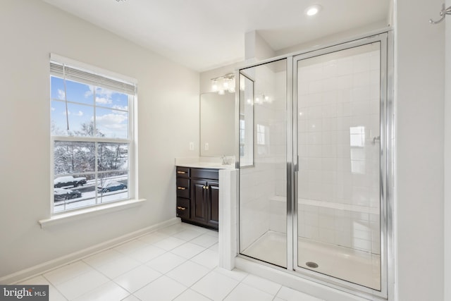 bathroom with a shower with door, vanity, and tile patterned floors