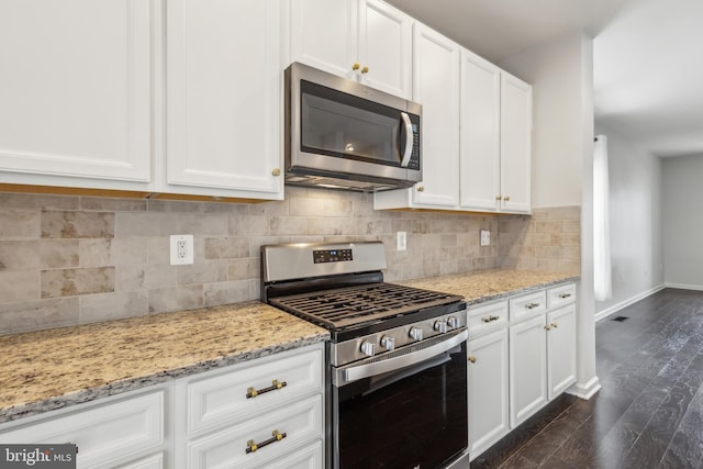 kitchen featuring white cabinetry, dark hardwood / wood-style floors, stainless steel appliances, light stone countertops, and backsplash